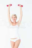 Happy blonde woman lifting dumbbells