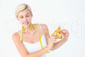 Pretty blonde choosing between eating pizza or not