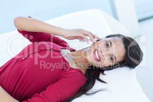 Pretty woman on the phone lying on her bed