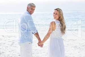 Happy couple standing by the sea and holding hands