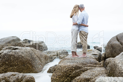 Happy couple standing on the rock and looking at the sea