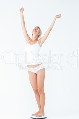 Happy woman standing on a scales spreading her arms