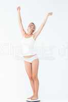 Happy woman standing on a scales spreading her arms