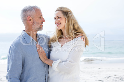 Happy couple smiling at each other by the sea