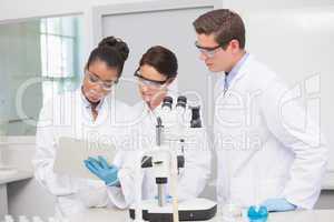 Scientists working with microscope and taking notes