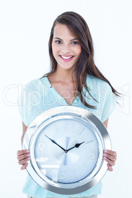 Pretty brunette holding a clock smiling at camera