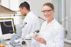 Scientist examining petri dish smiling at camera