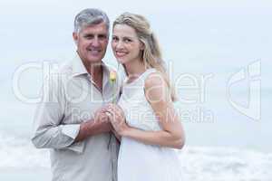 Happy couple smiling at camera and holding a flower