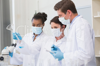 Scientists looking at beaker and taking notes