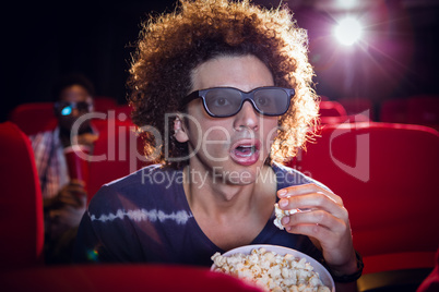 Young man watching a 3d film and eating popcorn