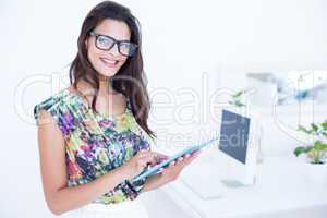 Smiling beautiful brunette standing in front of her computer