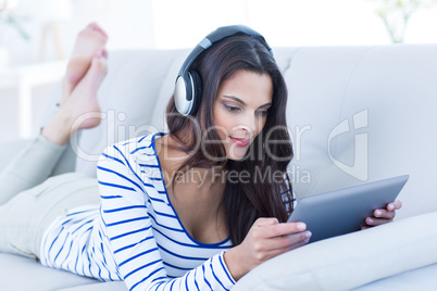 Smiling beautiful brunette listening music while using her table