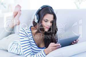 Smiling beautiful brunette listening music while using her table