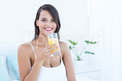 Pretty woman looking at camera holding glass of juice