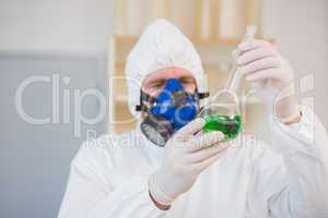 Scientist in protective suit examining green precipitate