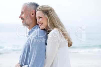 Happy couple hugging each other and looking at the sea