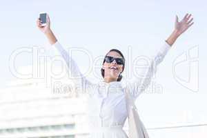Euphoric woman holding smartphone with hands up