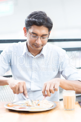 Handsome man eating food at cafeteria.