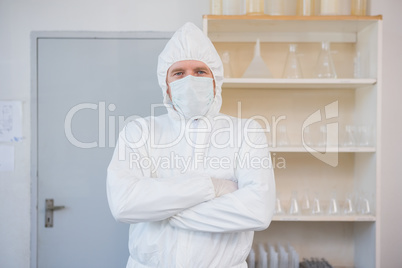 Scientist in protective suit looking at camera with arms crossed