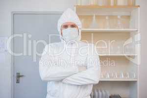 Scientist in protective suit looking at camera with arms crossed