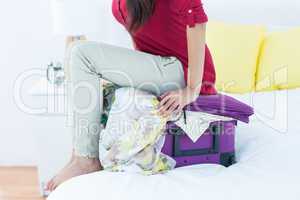 Woman sitting down on top of her suitcase