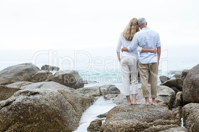 Happy couple standing on the rock and looking at the sea