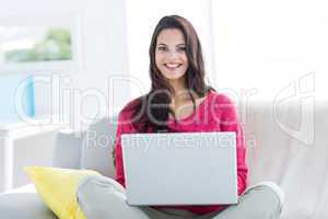Smiling beautiful brunette doing online shopping on the couch