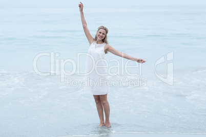 Smiling blonde in white dress standing by the sea