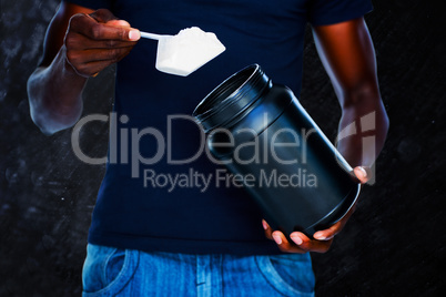 Composite image of mid section of man holding a scoop of protein