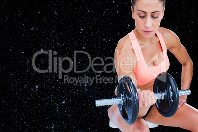 Composite image of strong woman doing bicep curl with large dumb