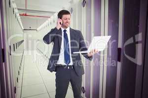 Composite image of businessman talking on phone holding laptop