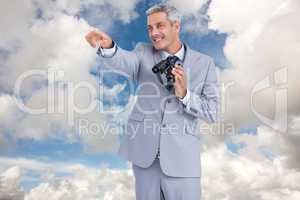 Composite image of businessman holding binoculars and pointing o