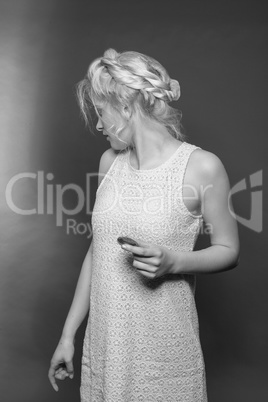 Blondes Mädchen im Minikleid und stylischer Frisur mit Keks in der Hand sieht nach hinten über Ihre Schulter