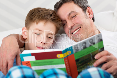 Son and father reading book together