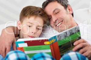 Son and father reading book together
