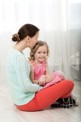 Mother kissing dear little daughter