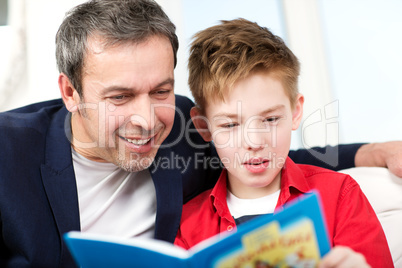 Dad and son reading a book at home