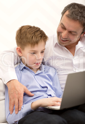 Father watching son working with laptop