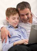 Happy dad and son with laptop at home