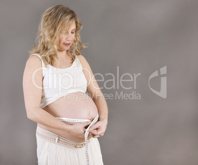 schwangere Frau mit Maßband
