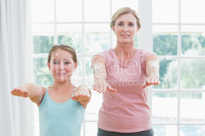 Happy mother and daughter doing yoga