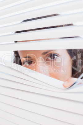 Curious woman looking through blinds