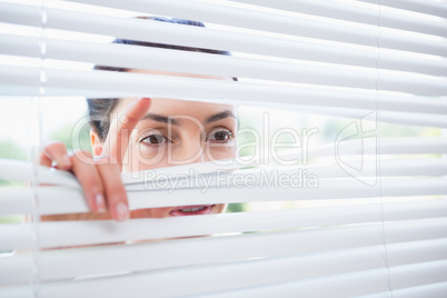 Woman peeking through blinds