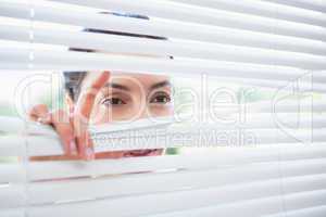 Woman peeking through blinds