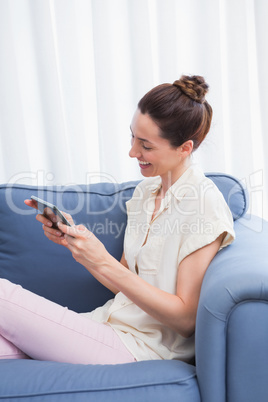 Casual brunette using tablet on couch