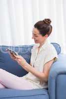 Casual brunette using tablet on couch