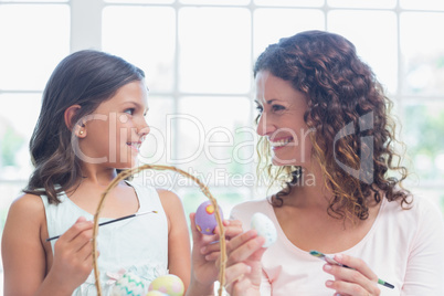 Happy mother and daughter painting easter eggs