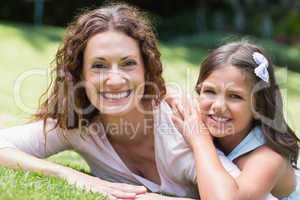 Happy mother and daughter lying on the grass