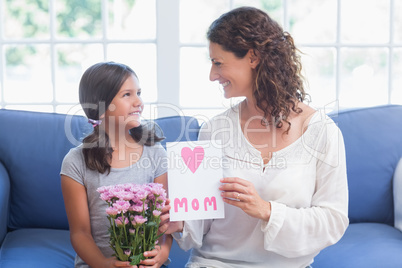 Cute girl offering flowers and card to her mother