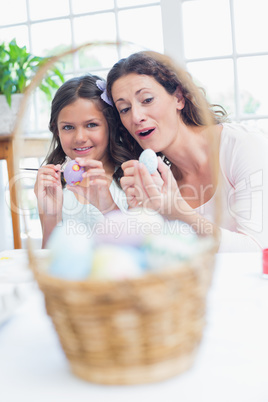 Happy mother and daughter painting easter eggs